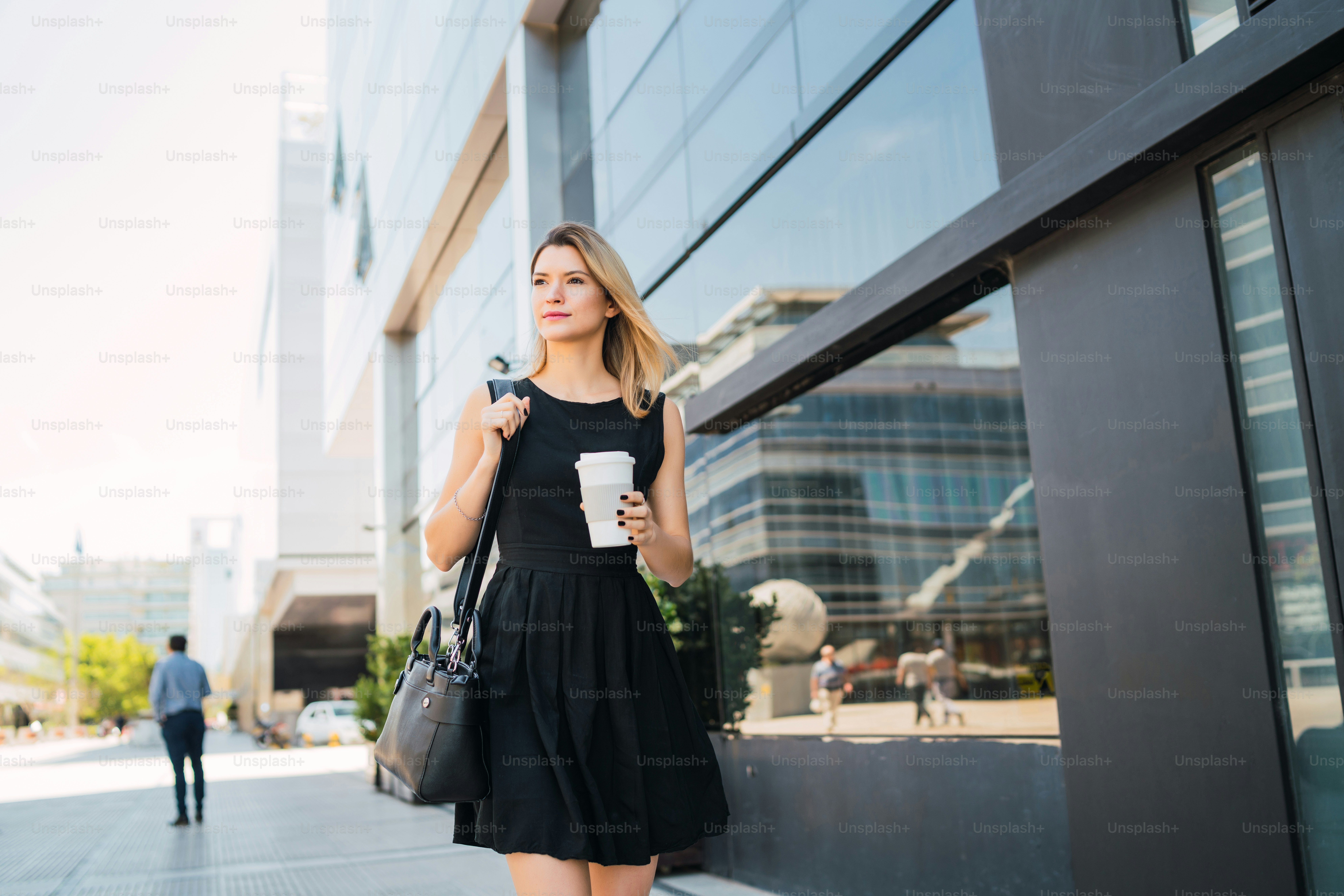 Portrait of young business woman walking to work while drinking takeaway coffee. Business and success concept.