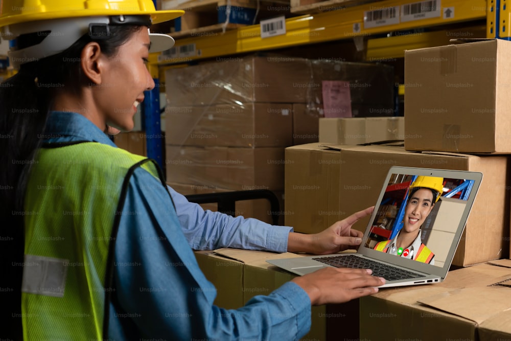 Warehouse staff talking on video call at computer screen in storage warehouse . Online software technology connects people working in logistic factory by virtual conference call on internet network .