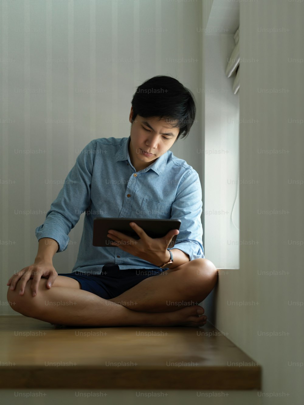 Portrait of a man using digital tablet while relaxed sitting at stair in his home