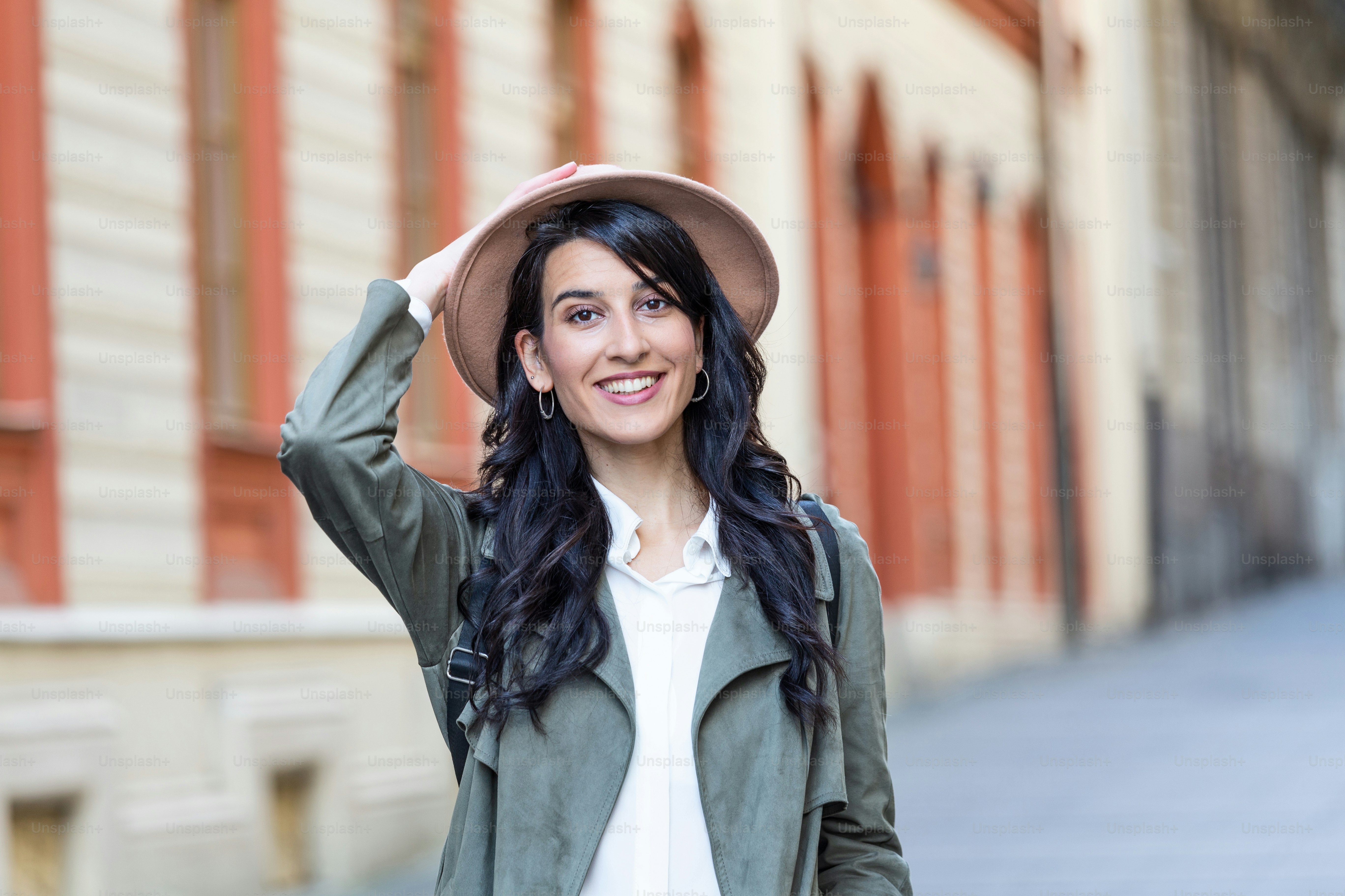 Sunny lifestyle fashion portrait of young stylish hipster woman walking on the street, wearing trendy outfit, hat, travel with backpack.