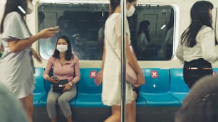 Crowd of people wearing face mask on a crowded public subway train travel . Coronavirus disease or COVID 19 pandemic outbreak and urban lifestyle problem in rush hour concept .