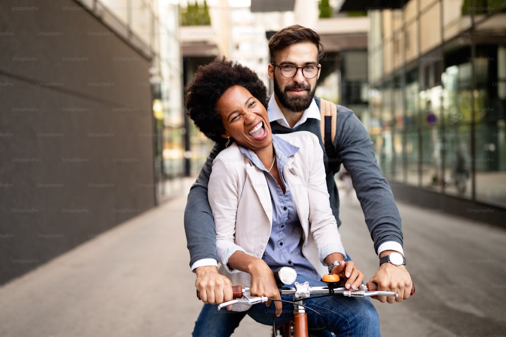 街で楽しんで自転車に乗る若い幸せなカップル
