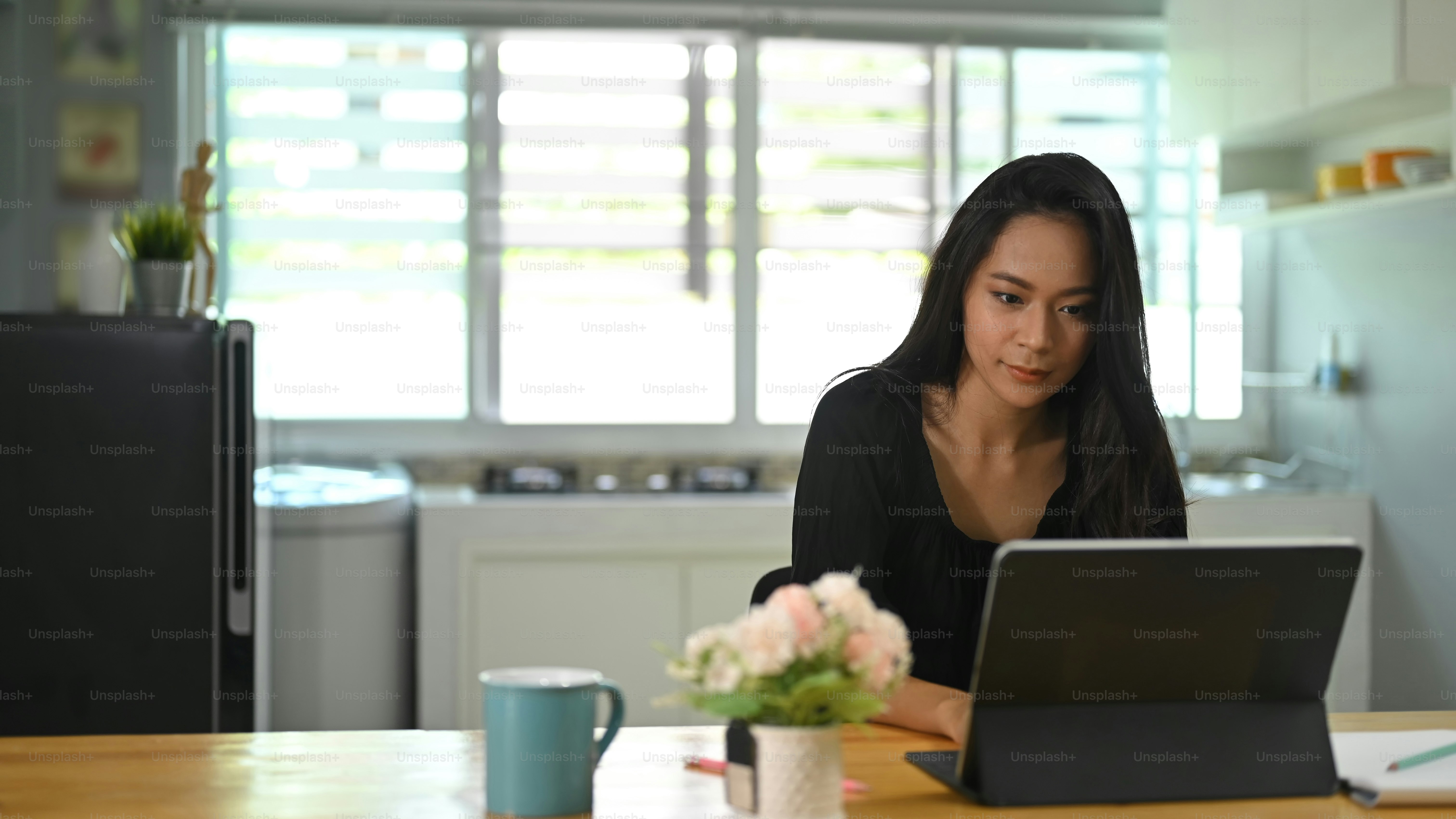 Asian woman working from home with tablet computer.