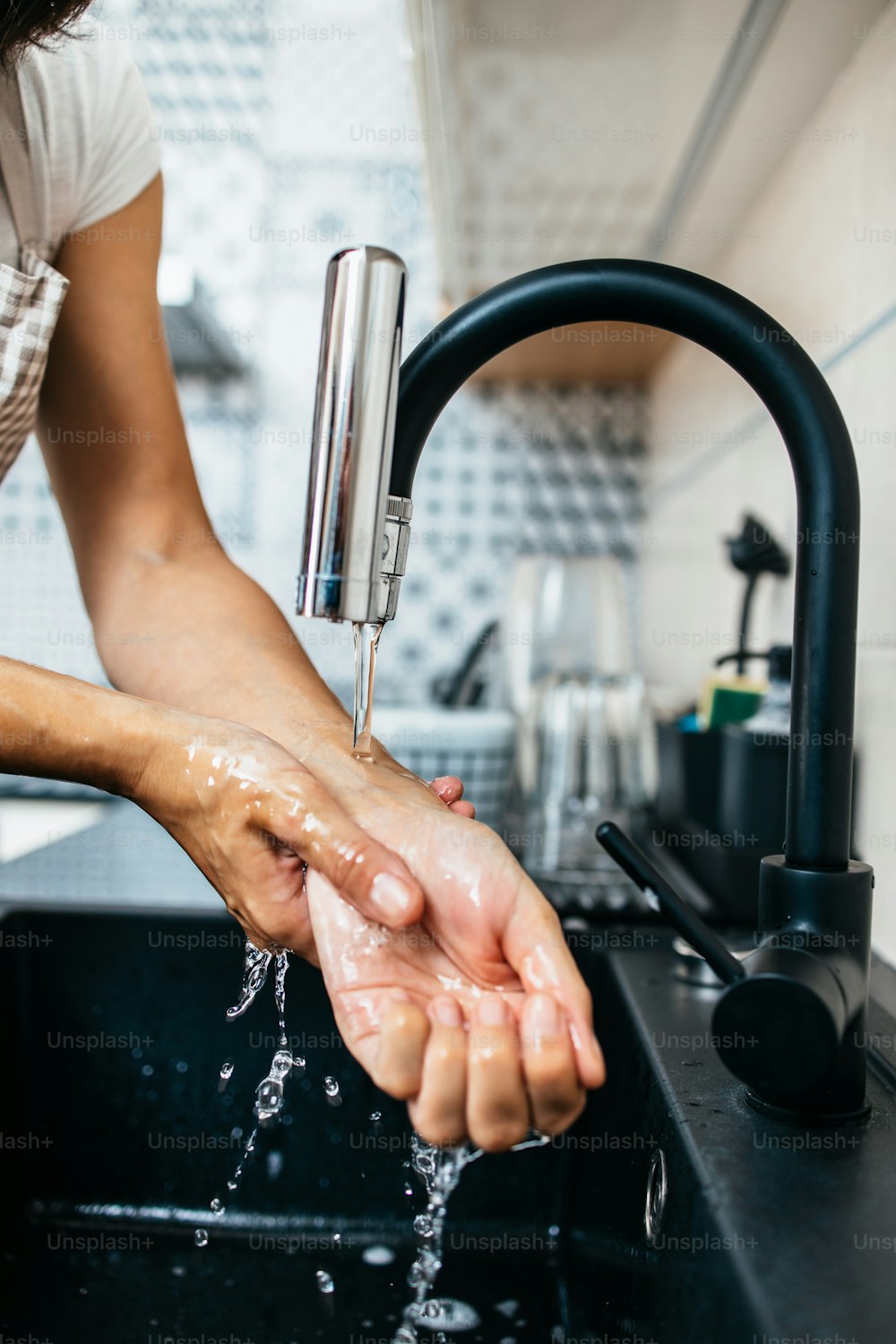 Young adult woman washing her hands on kitchen sink. Household and home and personal hygiene routine.
