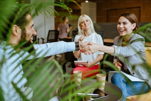Young business people shaking hands making an agreement with partner on the meeting in the modern coworking space. Selective focus on the hands.