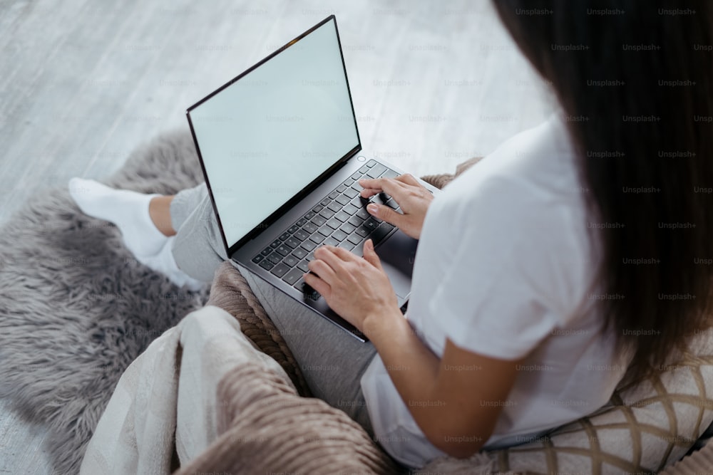 Cropped view of young adult woman working on laptop computer with copy space on display, spending free time at home