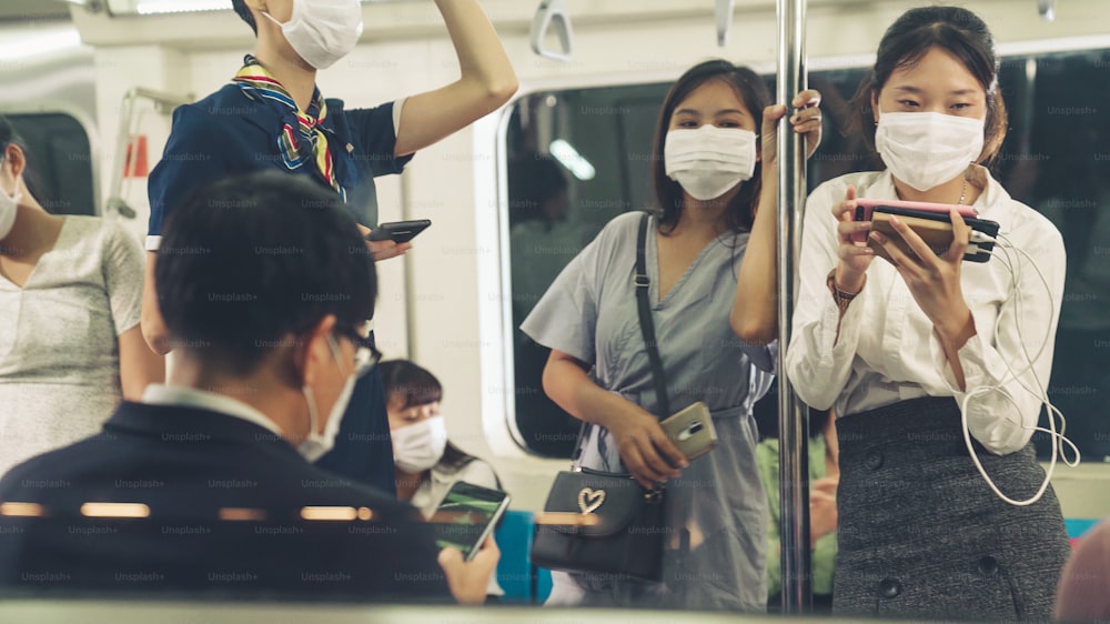 Crowd of people wearing face mask on a crowded public subway train travel . Coronavirus disease or COVID 19 pandemic outbreak and urban lifestyle problem in rush hour concept .