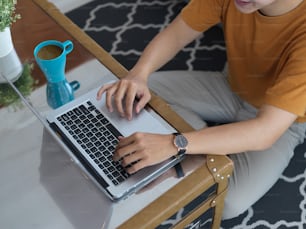 Overhead shot of male working at home with laptop on cfee table in living room