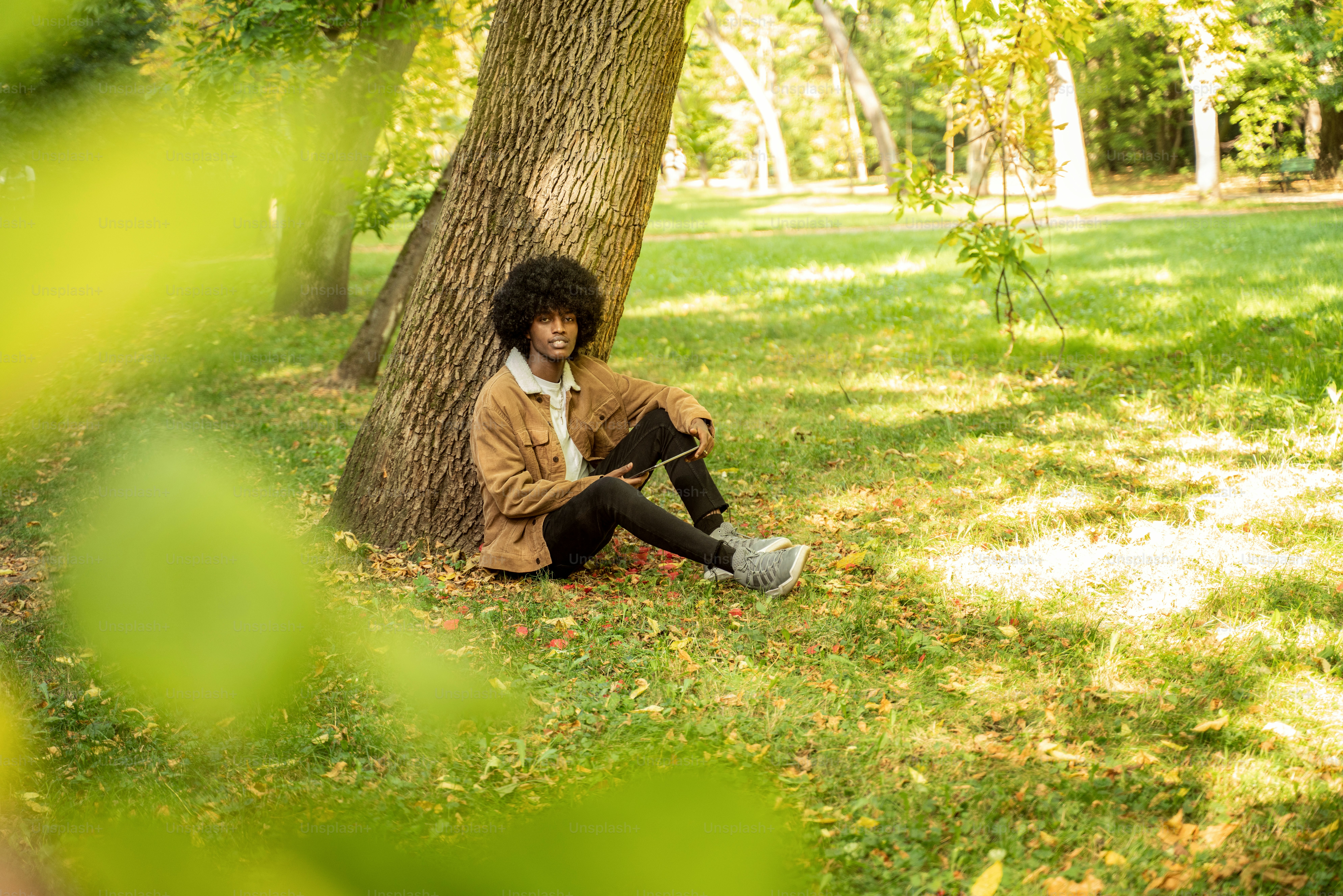 Young African American man using tablet in park.