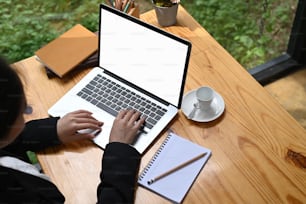 Arriba disparada mujer escribiendo en una computadora portátil con pantalla blanca.