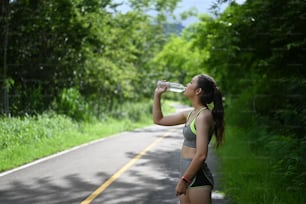 Portrait of beautiful fitness athlete woman drinking water after work out exercising.