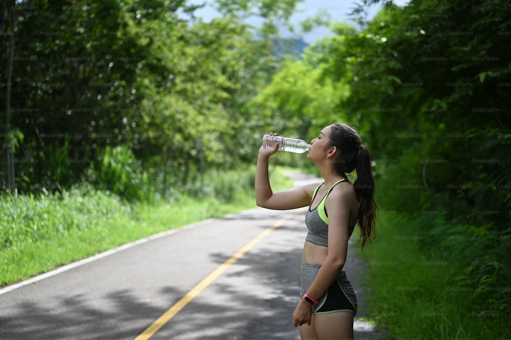 Portrait of beautiful fitness athlete woman drinking water after work out exercising.
