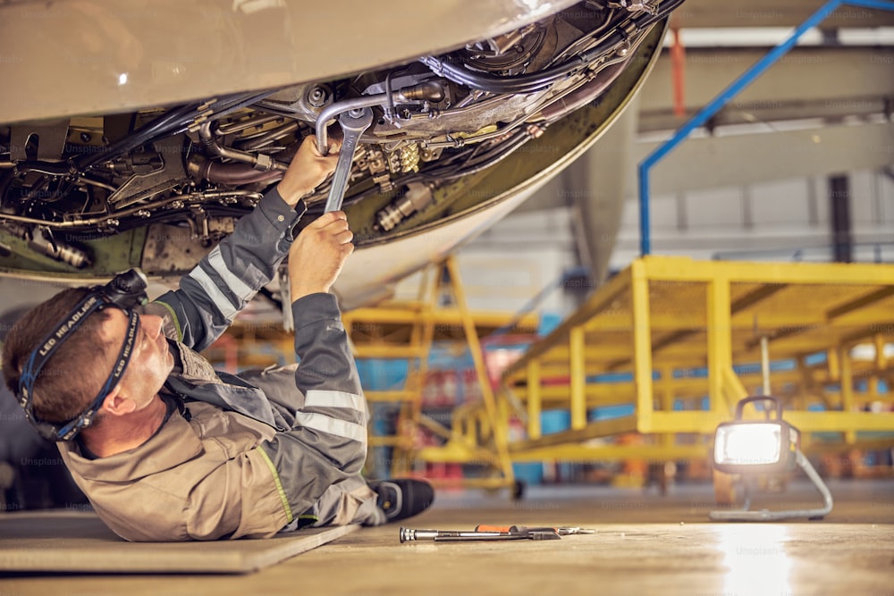 Side view of mechanic repairing the maintenance of a large engine of a passenger airplane in a hangar