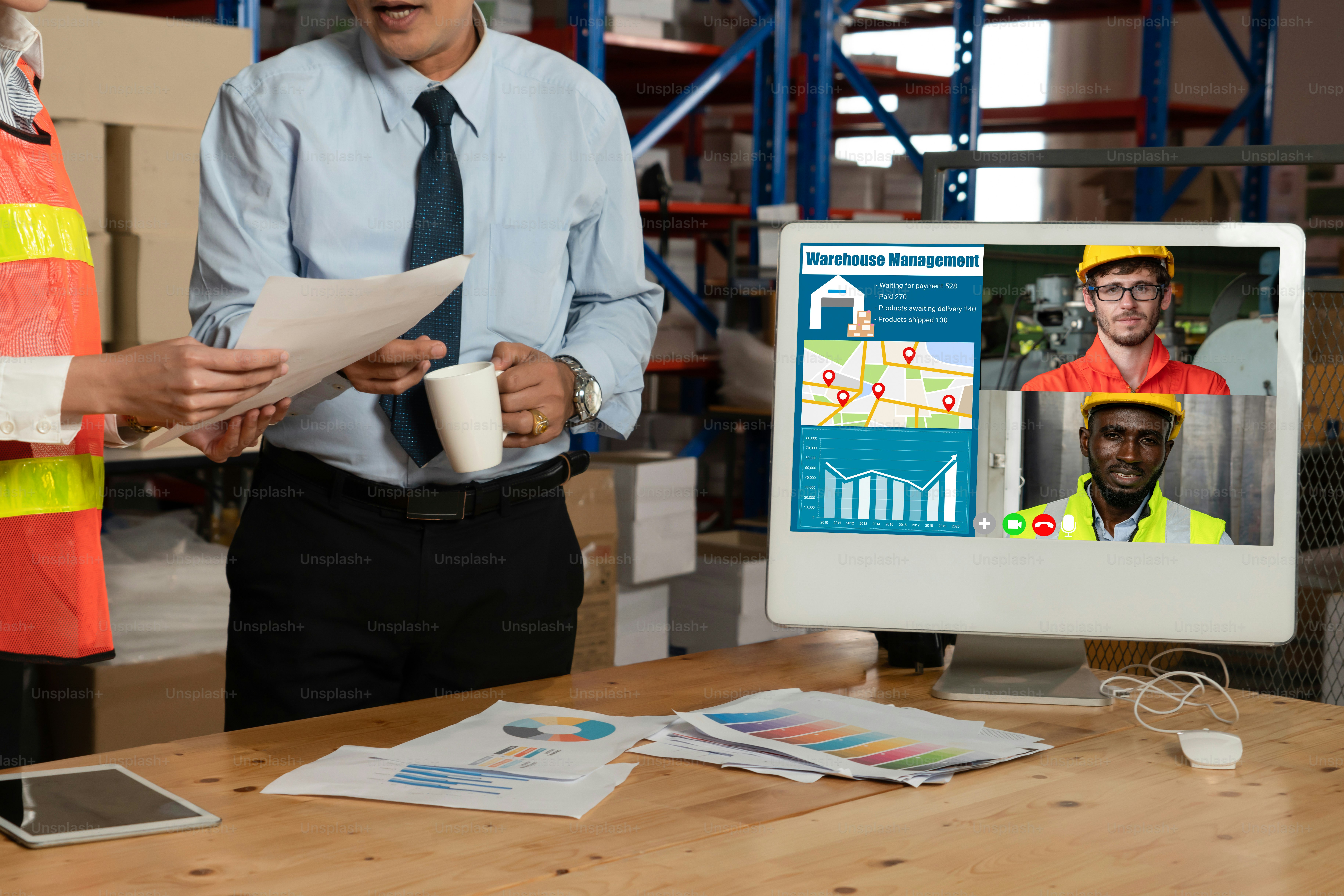Warehouse staff talking on video call at computer screen in storage warehouse . Online software technology connects people working in logistic factory by virtual conference call on internet network .