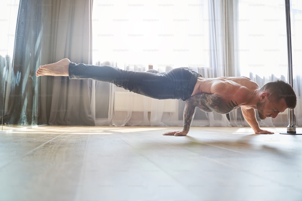 Portrait of muscular male pushing up on the wooden floor in the dance club