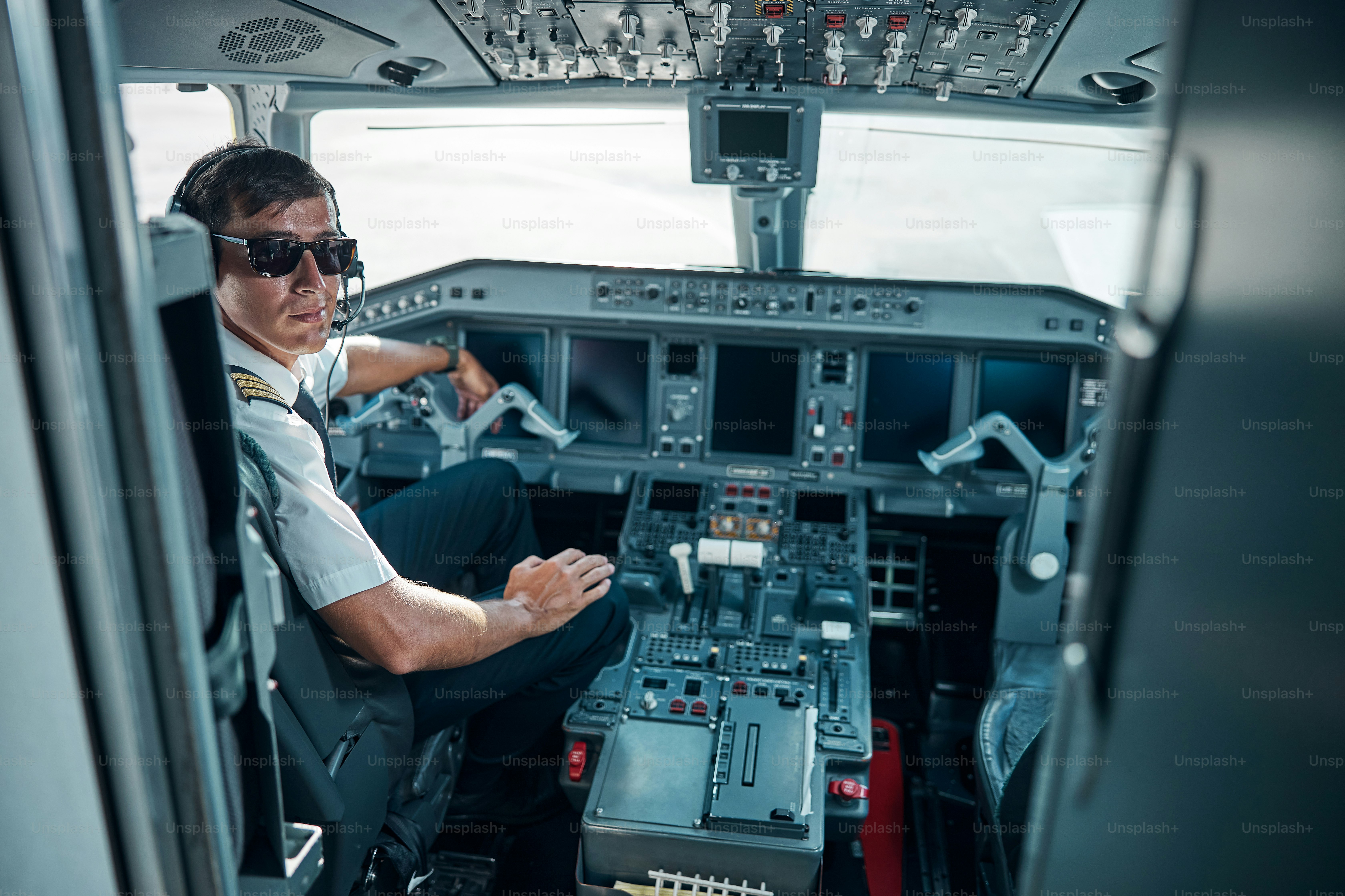 Jovem alegre em uniforme de avião e óculos perto do controle está se preparando para voar a jato