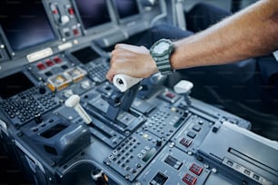 Draufsicht beschnittene Kopf-Nahaufnahme des Fliegers Hand auf Höhe der Steuerung im Cockpit während des Fluges
