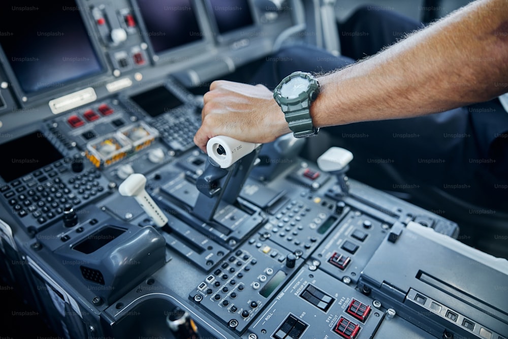 飛行中のコックピットのコントロールで水平に飛行士の手を振り絞る飛行士の手の頭のクローズアップの上面図トリミング