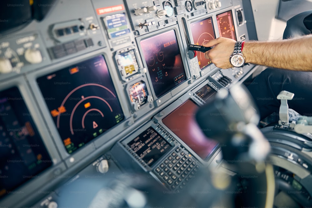 Retrato de vista lateral de cerca del piloto del hombre que controla el vuelo en el panel del tablero en la cabina