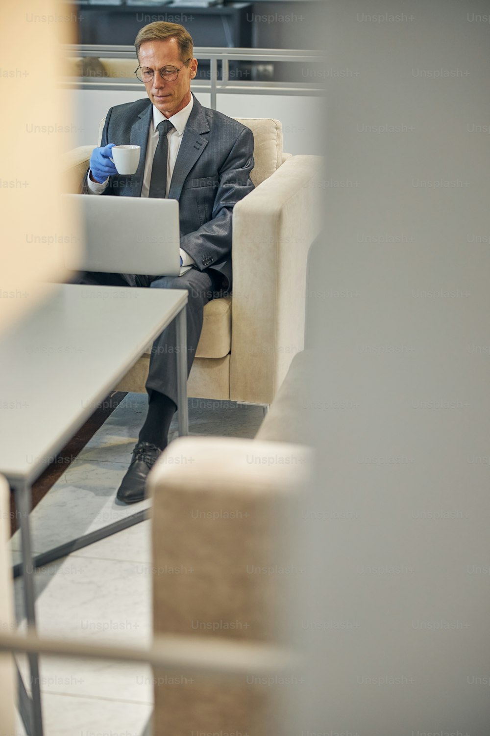 Top view of mature businessman wasting time before flight with notebook and cup of hot drink