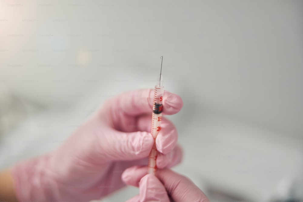 Close up of young woman in sterile gloves holding syringe for beauty injections