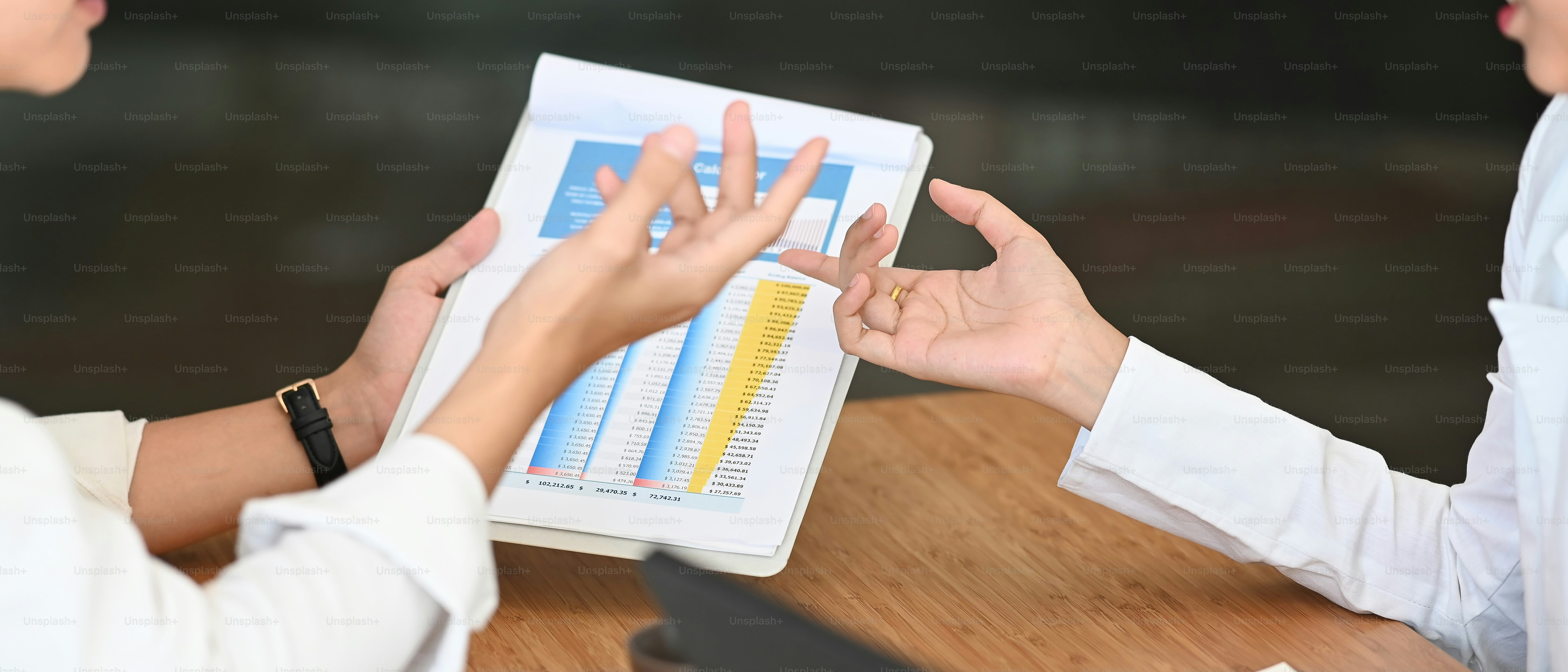 Cropped shot of business people talking discussing and analyzing financial document data charts and graphs in meeting room.