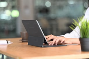 Close up of woman fingers typing a business document on the computer tablet at modern office.