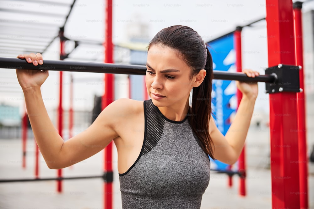 Beautiful athletic female is spending active day outdoors and having workout on open urban sports ground