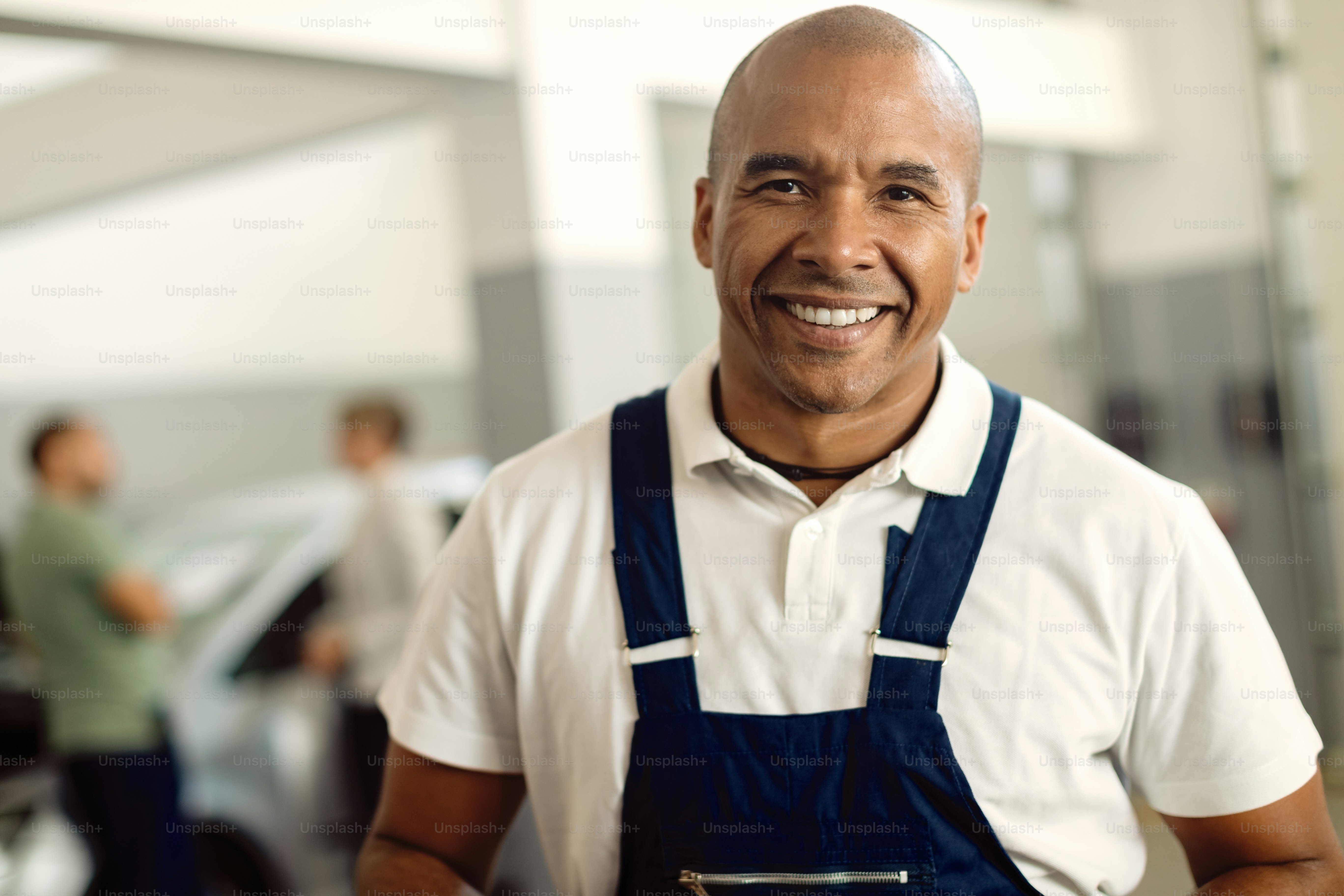 Portrait of happy African American repairman at car service workshop.