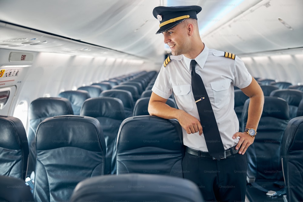 Waist up portrait of handsome confident captain of airplane looking into the distance in the aircraft