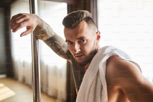 Close up portrait of strong muscular bearded man looking at the photo camera in the fitness studio