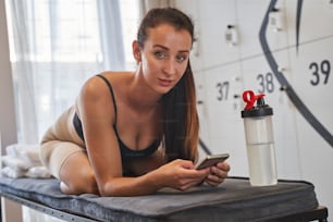 Close up portrait of happy beautiful woman waiting for a workout while she is looking at the photo camera in looker room