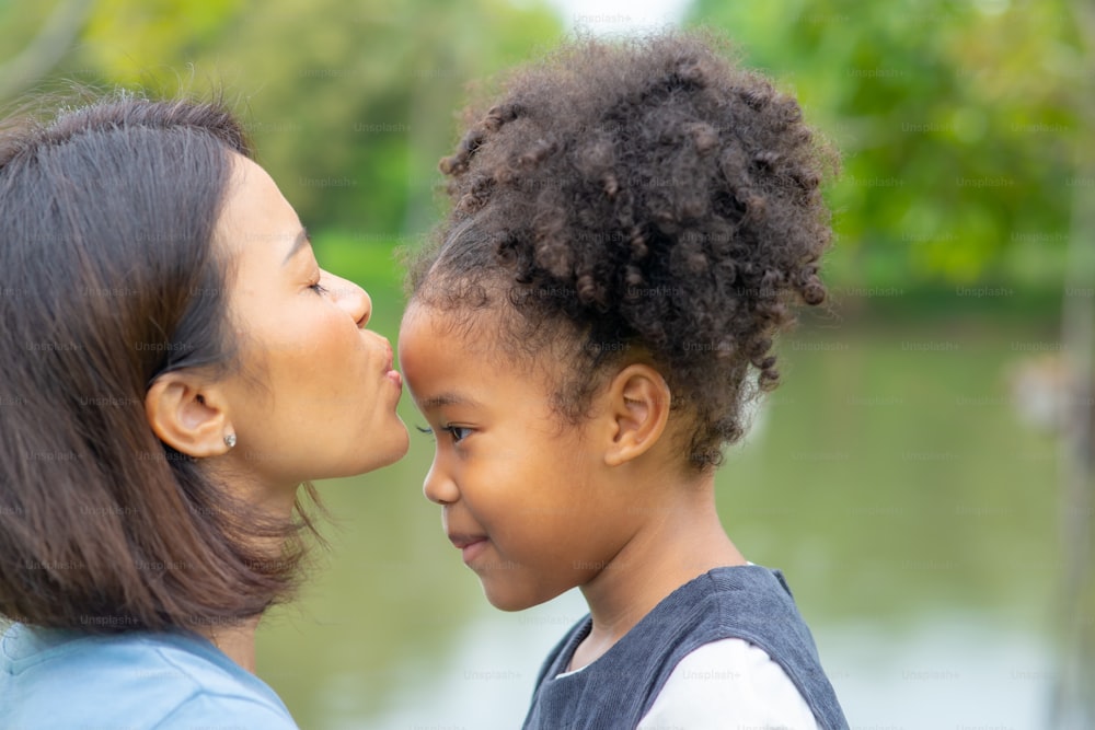 Mother kissing her mixed race daughter in the park