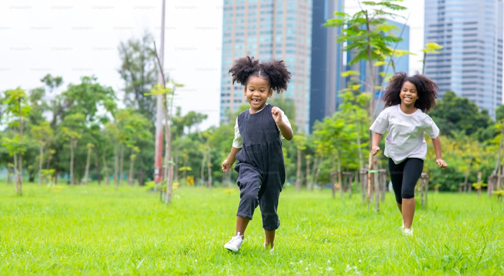 Menina feliz desfrutar e se divertir perseguindo seu irmão no parque.