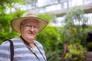 Happy senior man relaxing in park through the trees with soft focus