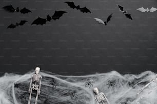 ハッピーハロウィンカード。黒い背景にコウモリ、骸骨、蜘蛛、蜘蛛の巣のシルエットが描かれたフラットレイ構図。