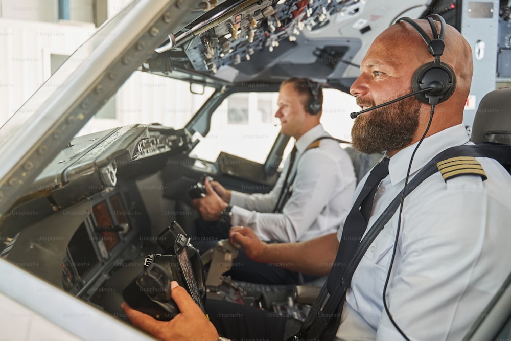 Pilotos experientes navegando no avião de passageiros de sua cabine e sorrindo alegremente