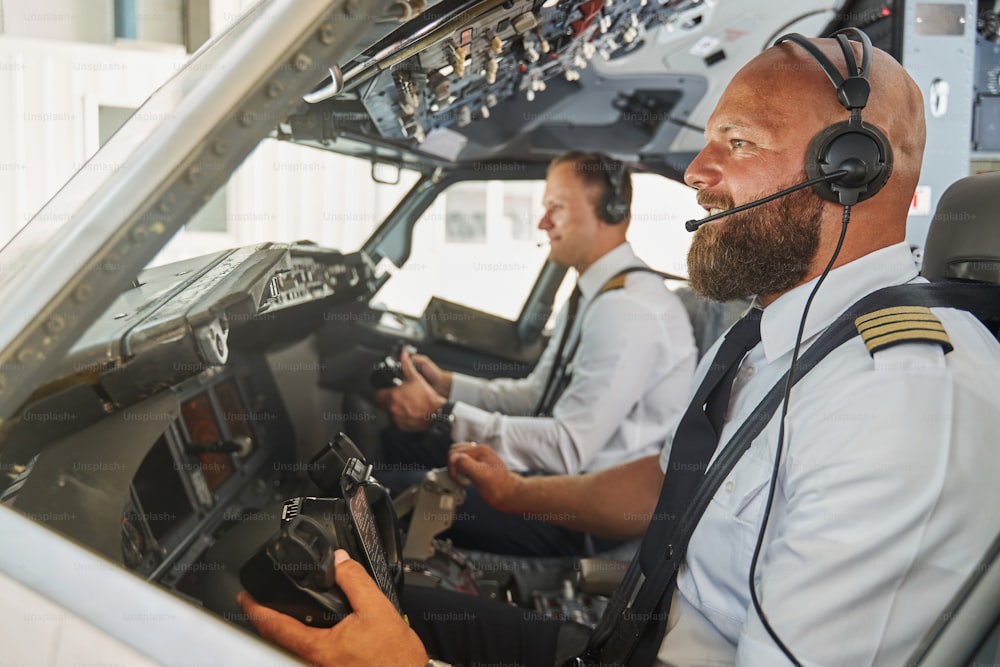 Experienced pilots navigating the passenger airplane from their cockpit and smiling cheerfully