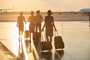 Mitglieder der internationalen Fluggesellschaft, die ihr Gepäck auf dem Weg zum Flugzeug tragen