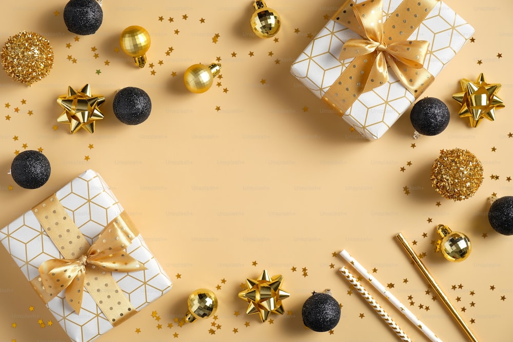 현대 크리스마스 구성입니다. 고급 선물 상자, 검은 색과 황금색 공 장식, 노란색 배경에 색종이 별들로 만든 프레임. 플랫 레이, 평면도, 복사 공간. 시즌 인사말 카드 템플릿입니다.