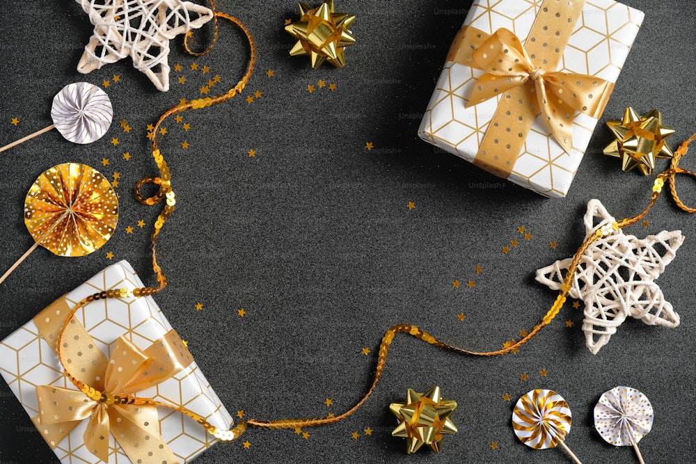 Sfondo natalizio nero con regali di lusso, decorazioni dorate, nastro, stelle, coriandoli. Posa piatta, vista dall'alto, dall'alto. Cornice di Natale, design del banner di vendita di Capodanno.