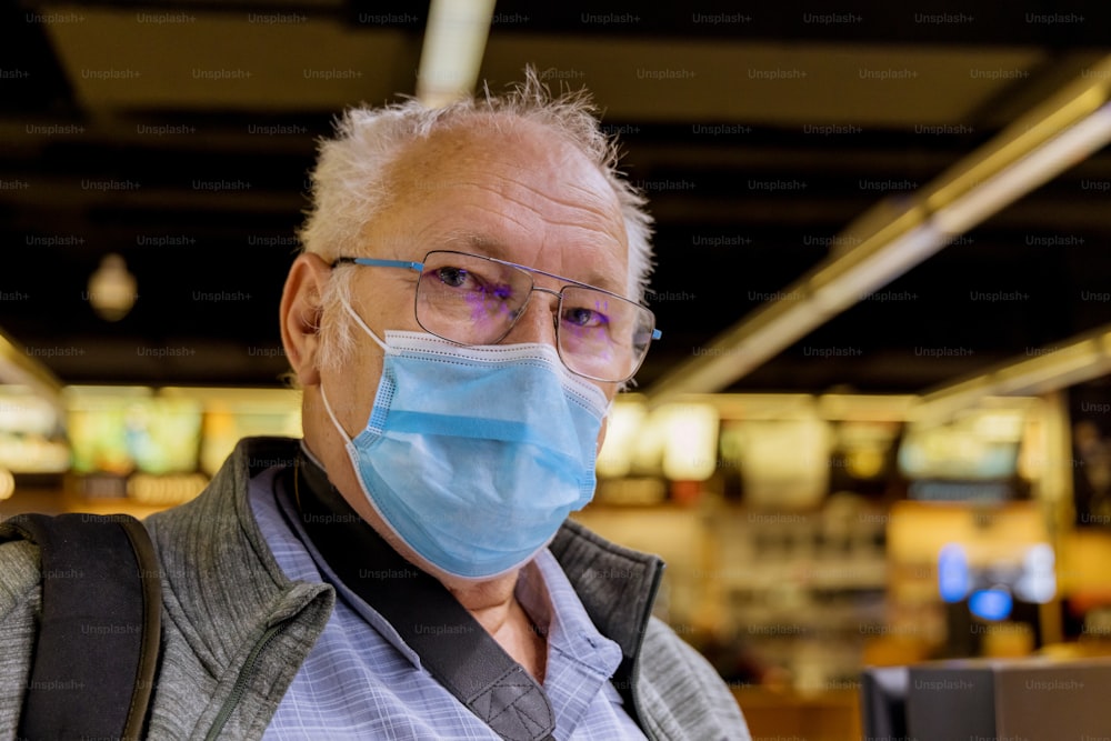 지하철 코로나 바이러스 전염병에 서있는 의료 마스크를 쓴 노인이 기차 지하철을 기대합니다.