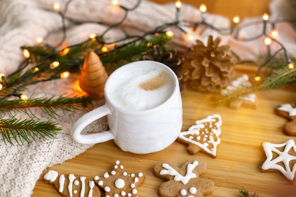 Christmas  gingerbread cookies, aromatic coffee, pine cones, fir branches and warm lights on wooden table. Cozy winter image. Merry Christmas and Happy Holidays!