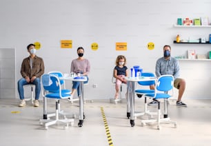 Vista frontal de personas con máscaras faciales en la sala de espera en el hospital, coronavirus, covid-19 y concepto de vacunación.