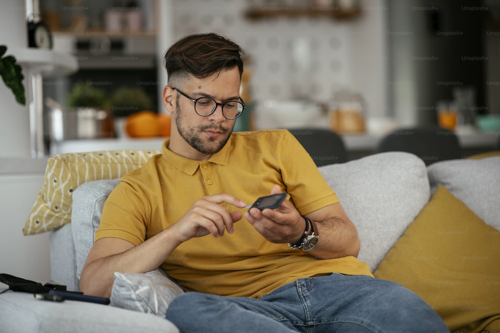 Man checking blood sugar level with glucometer. Young man measuring blood sugar level.