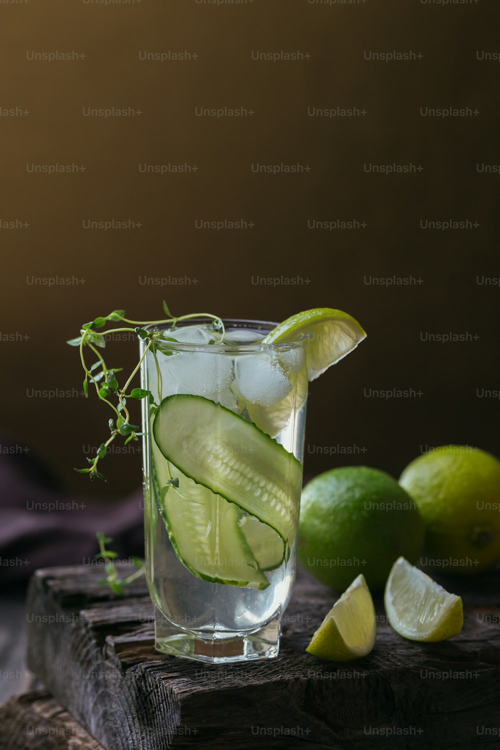 Glass of cucumber cocktail or mocktail, refreshing summer drink with crushed ice and sparkling water on wooden background.