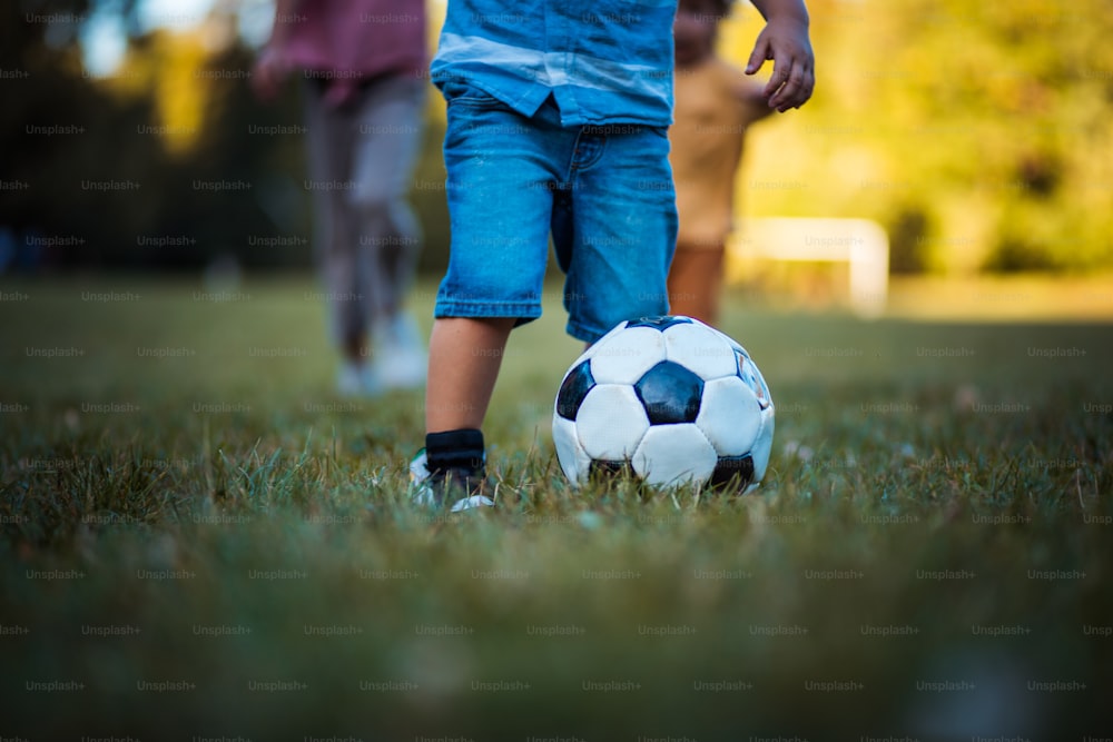 Tiempo de fútbol.  Piernas de niño pequeño jugando al fútbol en la hierba. Cerrar.