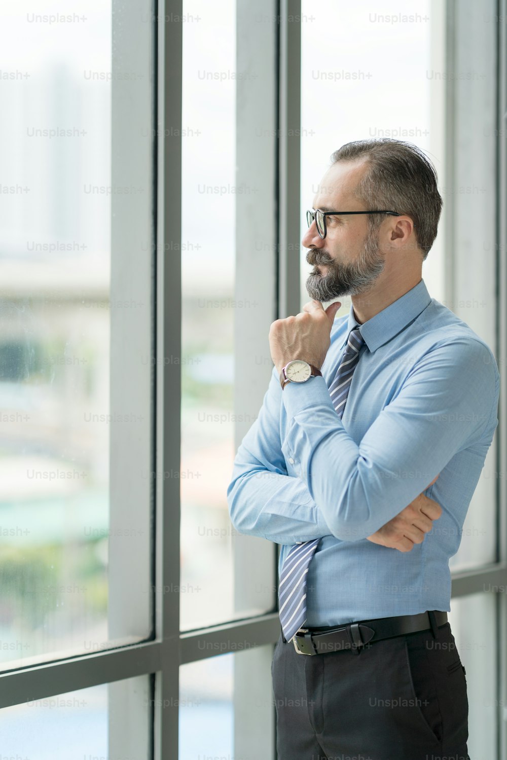 Hombre de negocios adulto, maestro, mentor mira por la gran ventana de su oficina. Trabaja en la oficina. Desarrollo de un nuevo proyecto empresarial