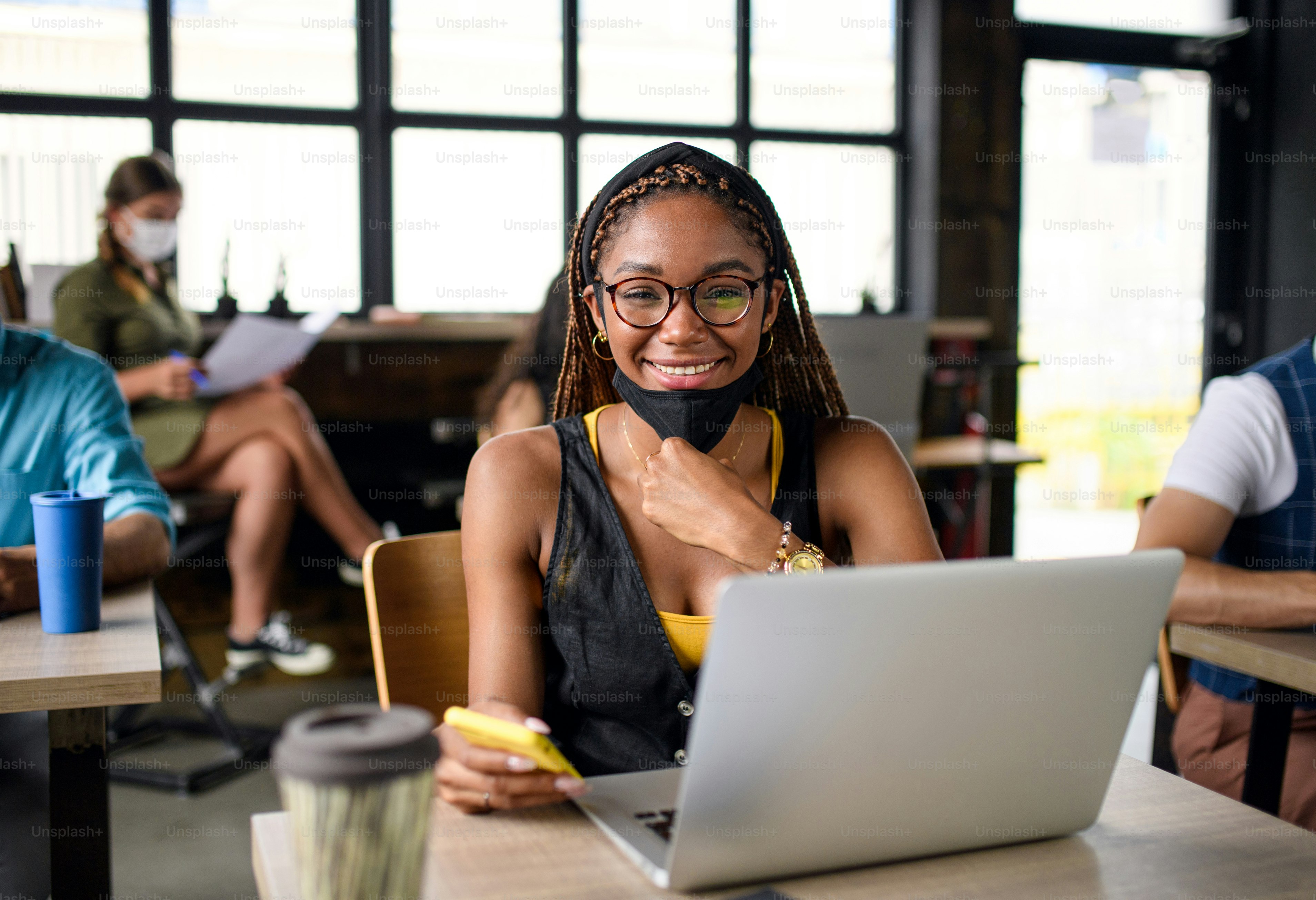 Business people with face masks working indoors in office, back to work after coronavirus lockdown.