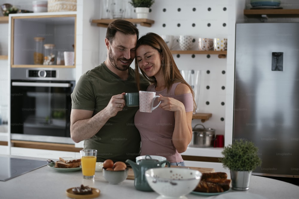 Young couple making breakfast at home. Loving couple eating sandwich and drinking coffee.